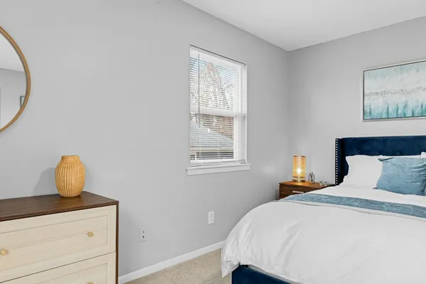 A repainted bedroom with a made bed, dresser and mirror.
