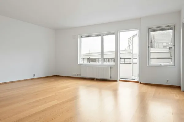 An empty room with bare wood floors and freshly painted white walls.