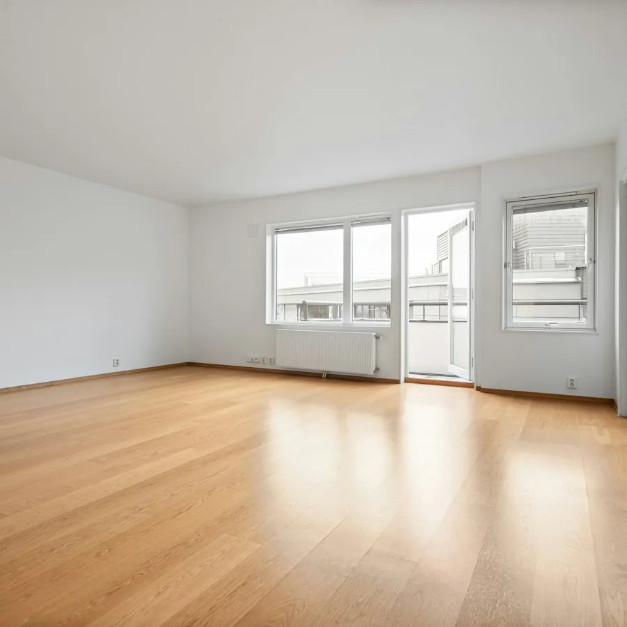 An empty room with bare wood floors and freshly painted white walls.