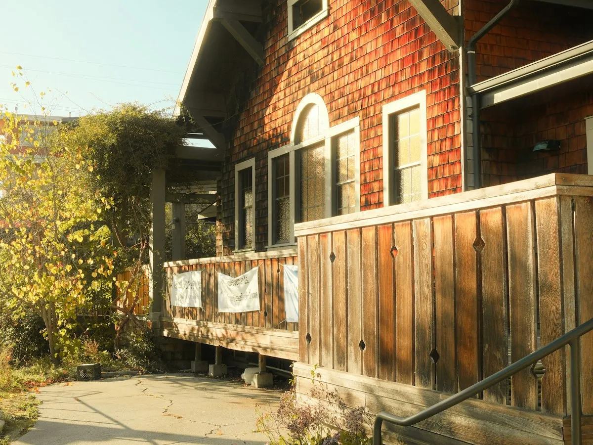 A wood-sided house with a red shingled exterior and a planted garden.