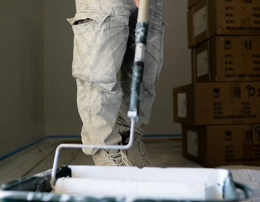 A painter rolling a fresh coat of colour onto an interior wall.